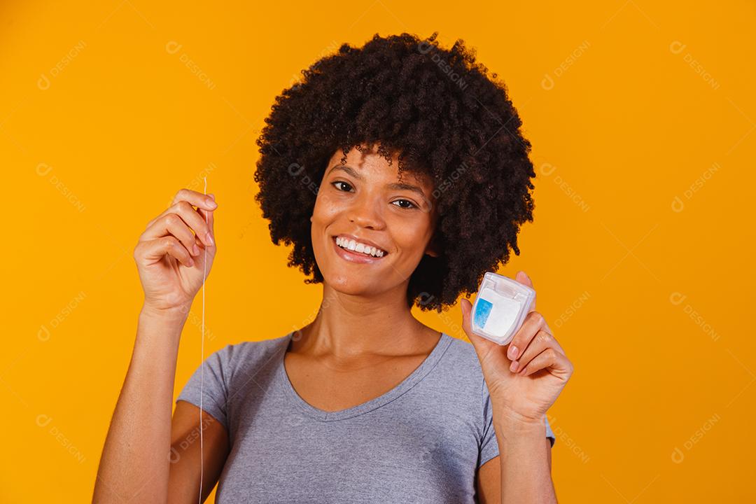 mulher afro passando fio dental nos dentes. conceito de saúde bucal