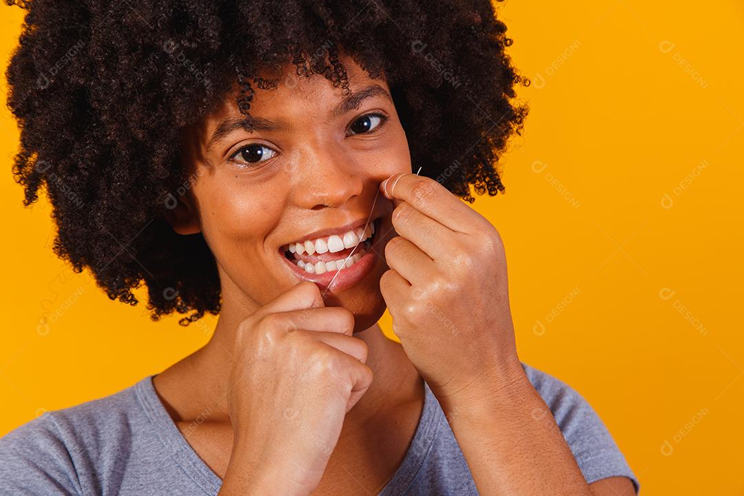 mulher afro passando fio dental nos dentes. conceito de saúde bucal