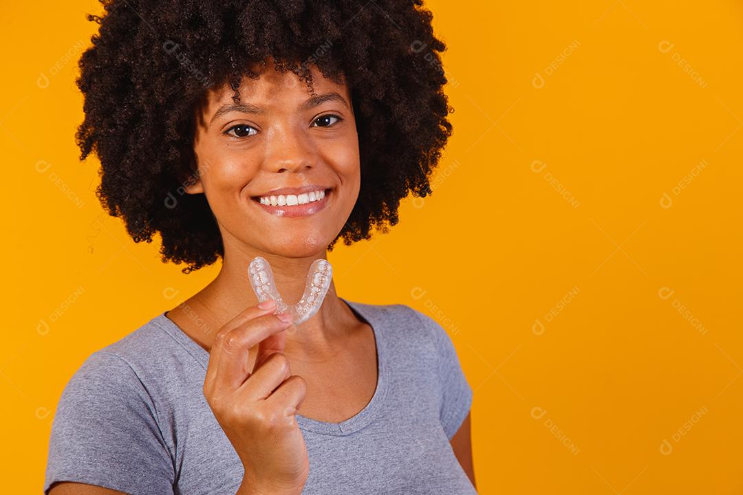 mulher afro segurando placa de clareamento. Dispositivo invisível.