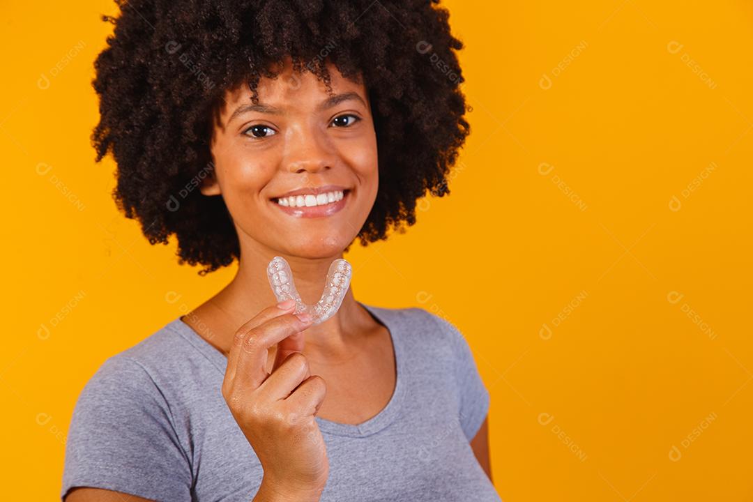 mulher afro segurando placa de clareamento. Dispositivo invisível.