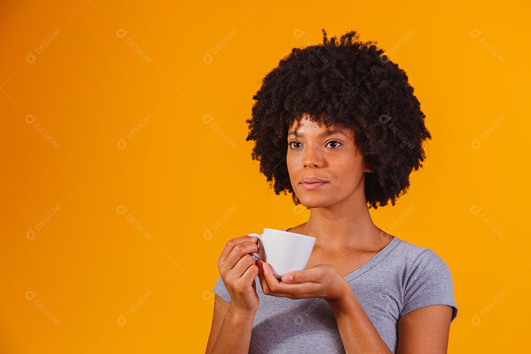 mulher afro tomando chá em fundo amarelo