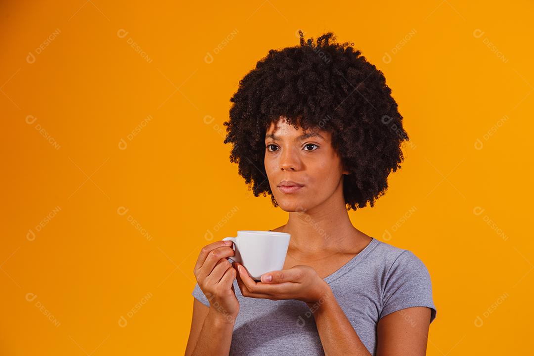 mulher afro tomando chá em fundo amarelo