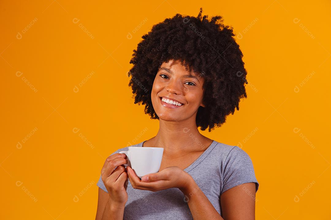 afro woman drinking tea on yellow background
