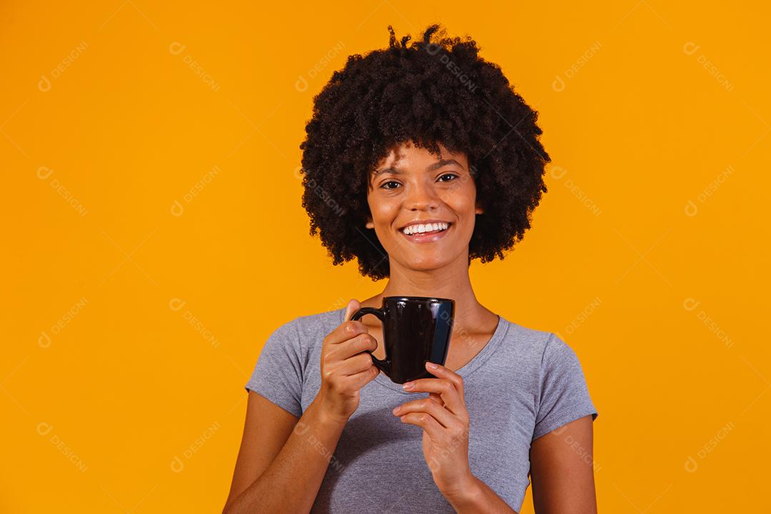 mulher afro tomando chá em fundo amarelo