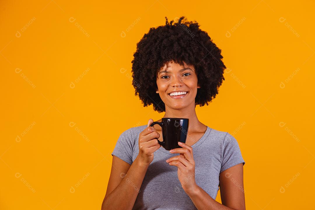 mulher afro tomando chá em fundo amarelo