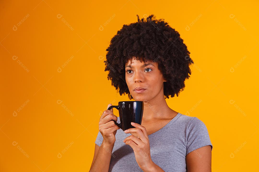 mulher afro tomando chá em fundo amarelo