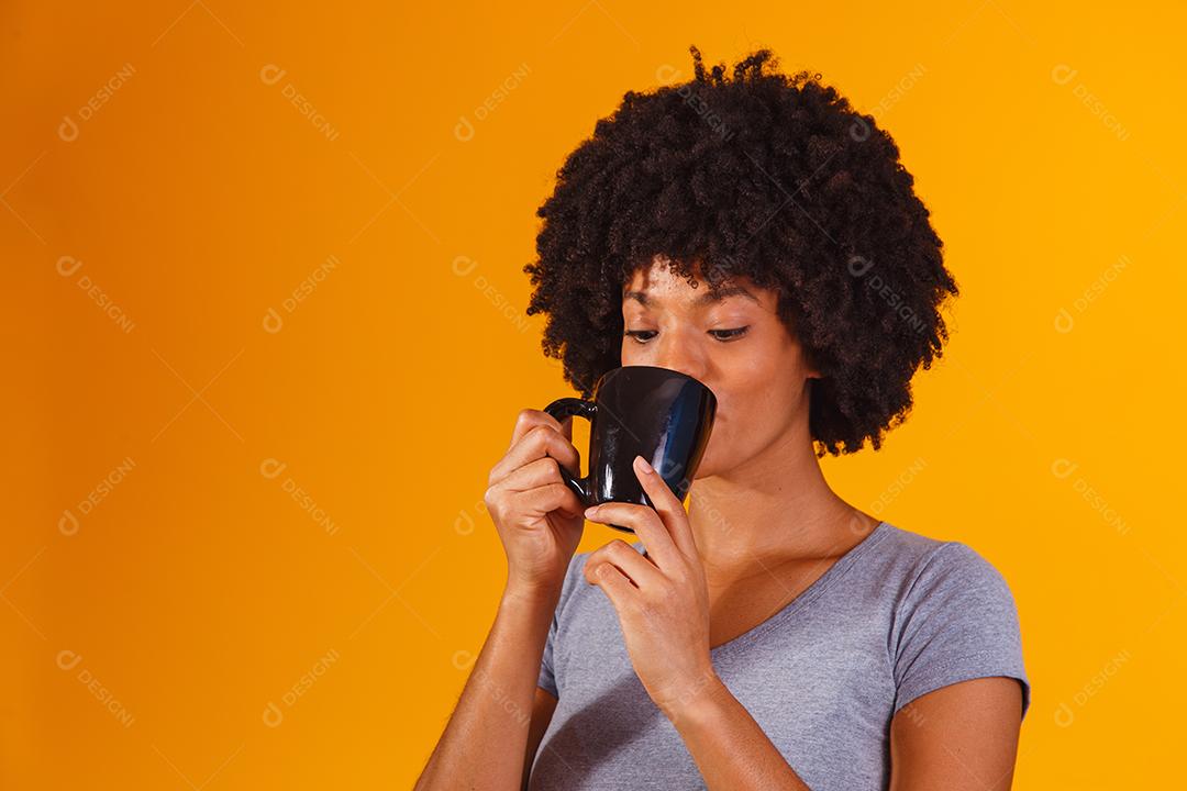 mulher afro tomando chá em fundo amarelo