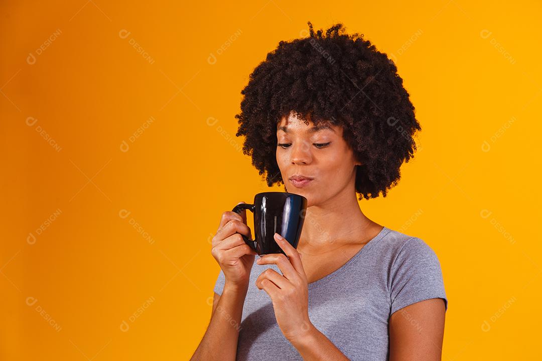 mulher afro tomando chá em fundo amarelo