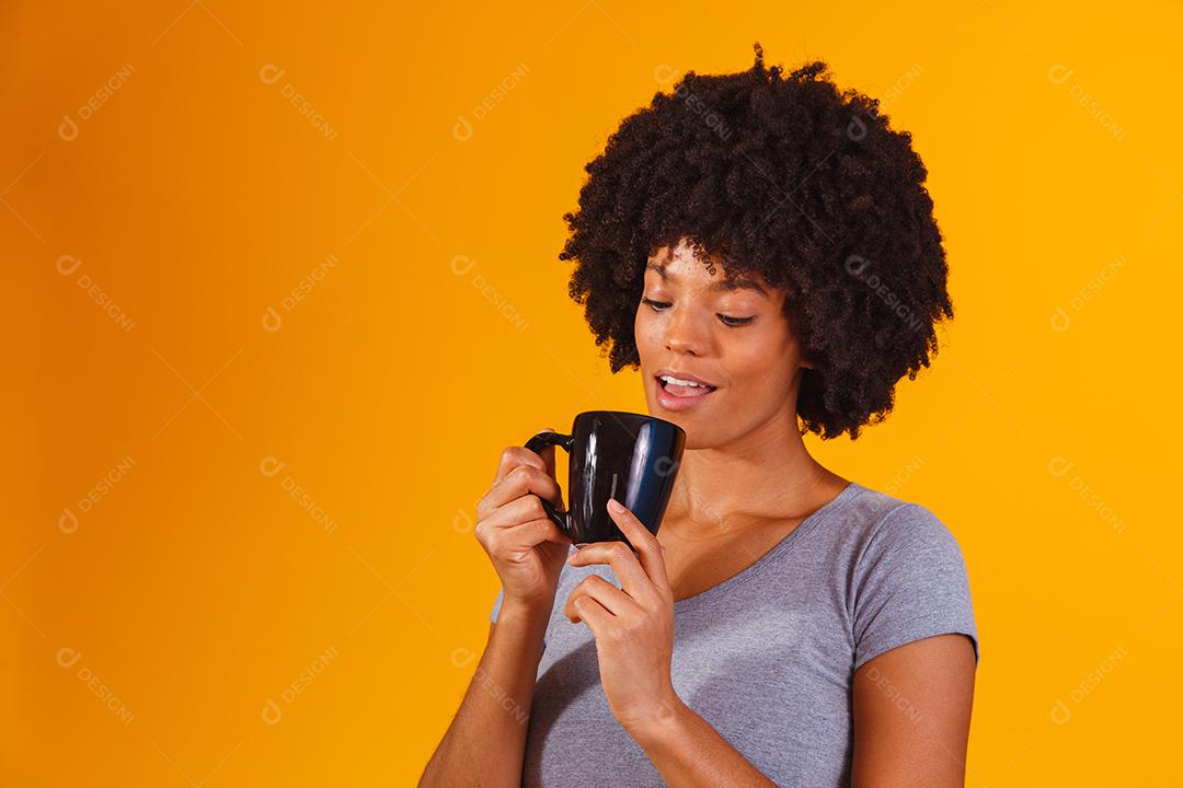 mulher afro tomando chá em fundo amarelo