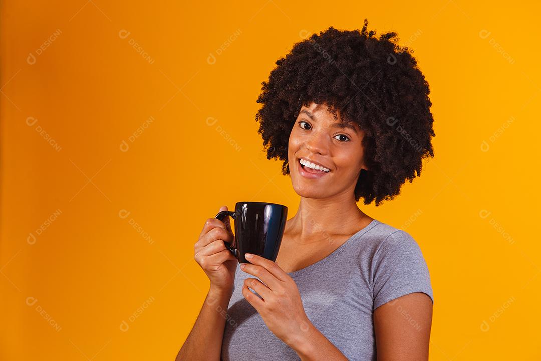 mulher afro tomando chá em fundo amarelo