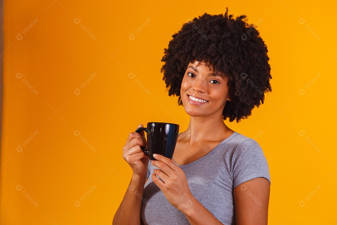 mulher afro tomando chá em fundo amarelo