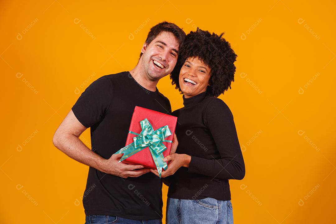 Retrato de um lindo casal em fundo amarelo com um presente