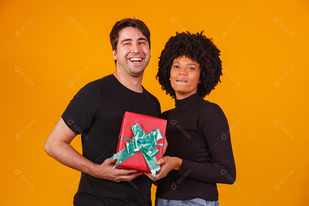 Retrato de um lindo casal em fundo amarelo com um presente