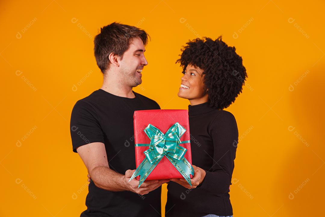 Retrato de um lindo casal em fundo amarelo com um presente