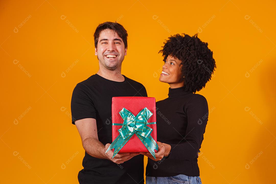 Portrait of a beautiful couple on a yellow background with a gift
