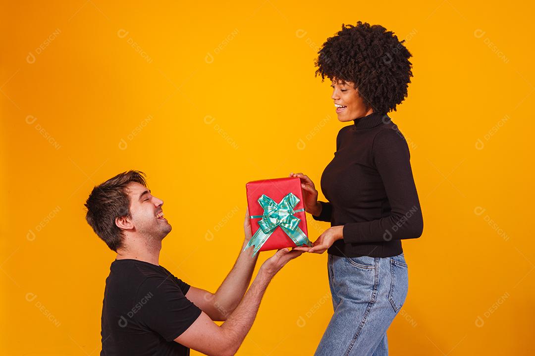 Portrait of a beautiful couple on a yellow background with a gift