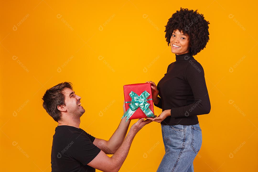 Retrato de um lindo casal em fundo amarelo com um presente