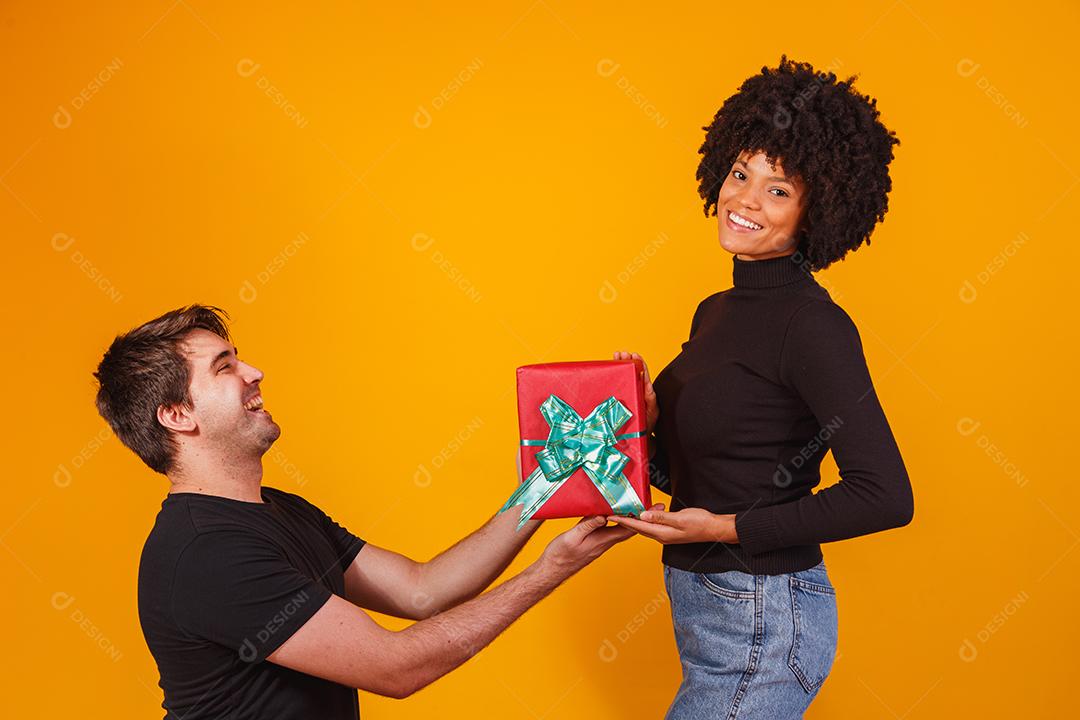 Retrato de um lindo casal em fundo amarelo com um presente