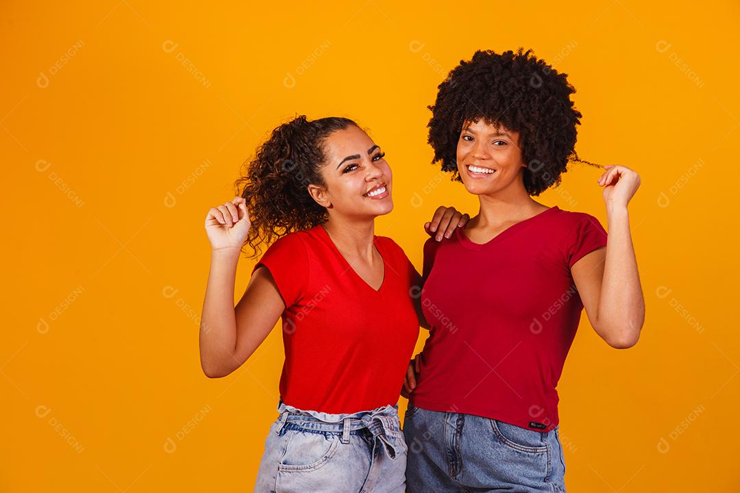 Jovens amigas afro bonitas e felizes sorrindo para a câmera.