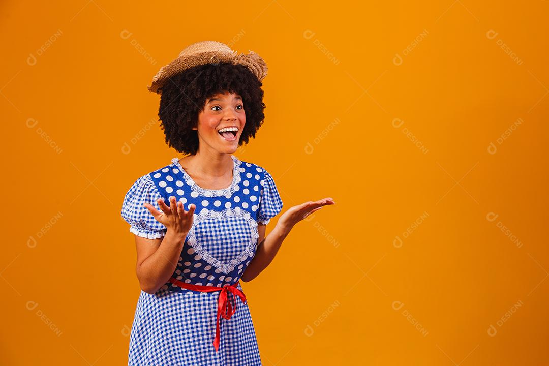 Mulher afro brasileira vestindo roupas típicas para a Festa Junina em fundo amarelo