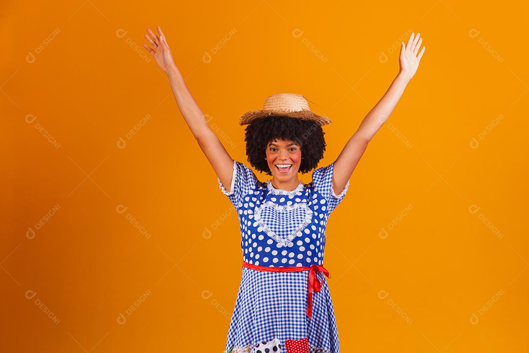 Mulher afro brasileira vestindo roupas típicas para a Festa Junina em fundo amarelo