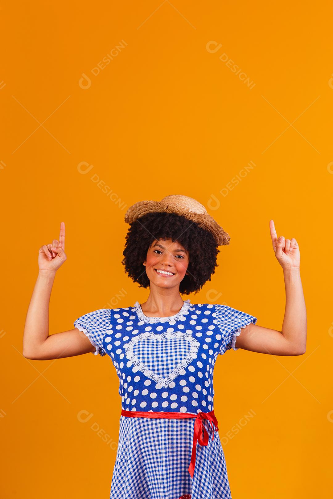 Mulher afro brasileira vestindo roupas típicas para a Festa Junina em fundo amarelo