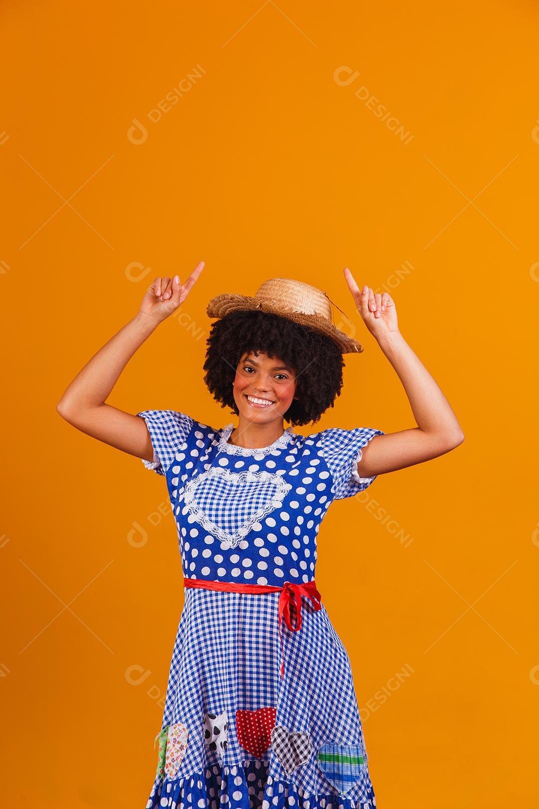Mulher afro brasileira vestindo roupas típicas para a Festa Junina em fundo amarelo