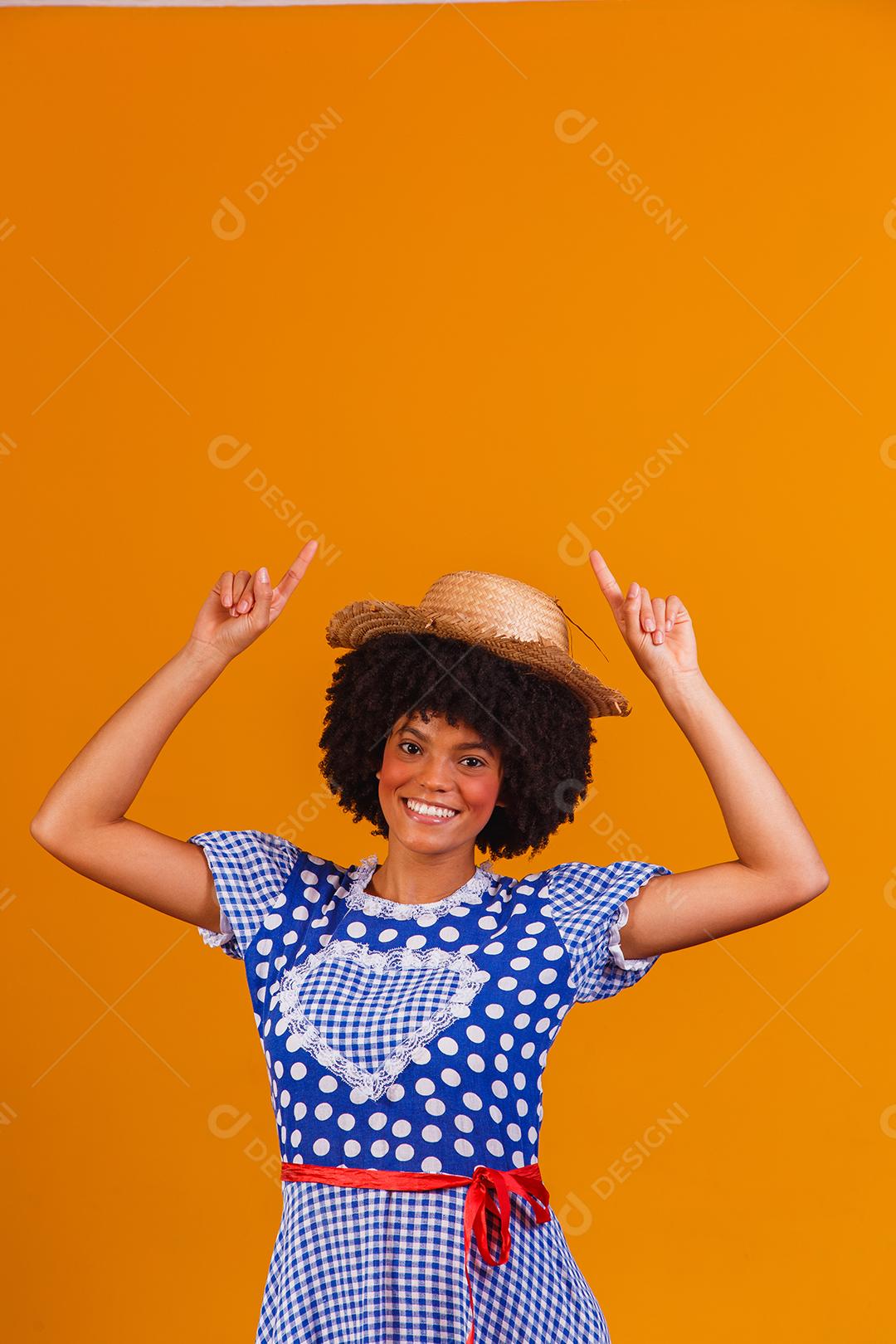 Mulher afro brasileira vestindo roupas típicas para a Festa Junina em fundo amarelo