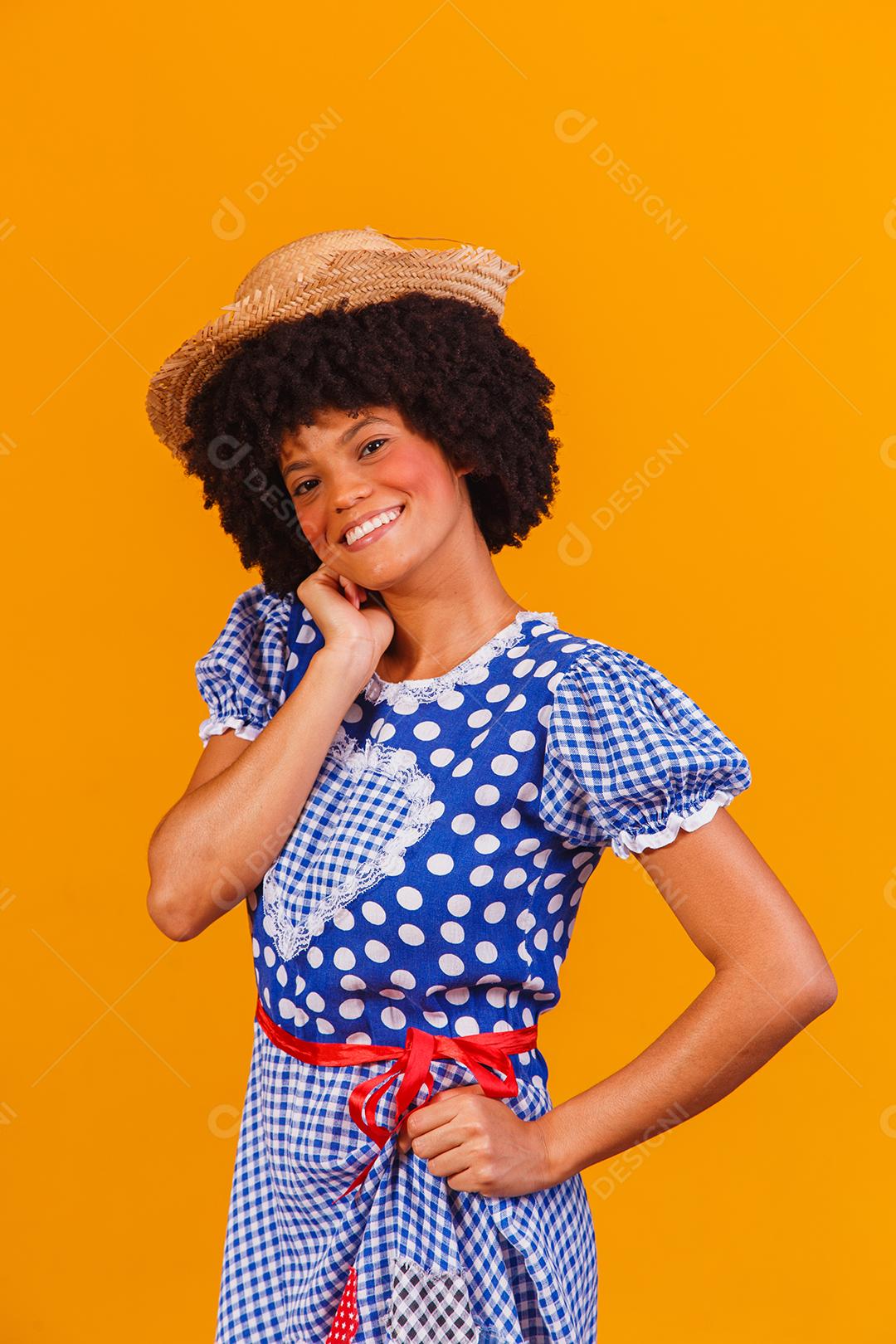 Mulher afro brasileira vestindo roupas típicas para a Festa Junina em fundo amarelo