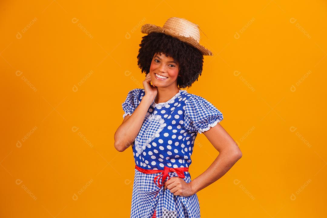 Mulher afro brasileira vestindo roupas típicas para a Festa Junina em fundo amarelo