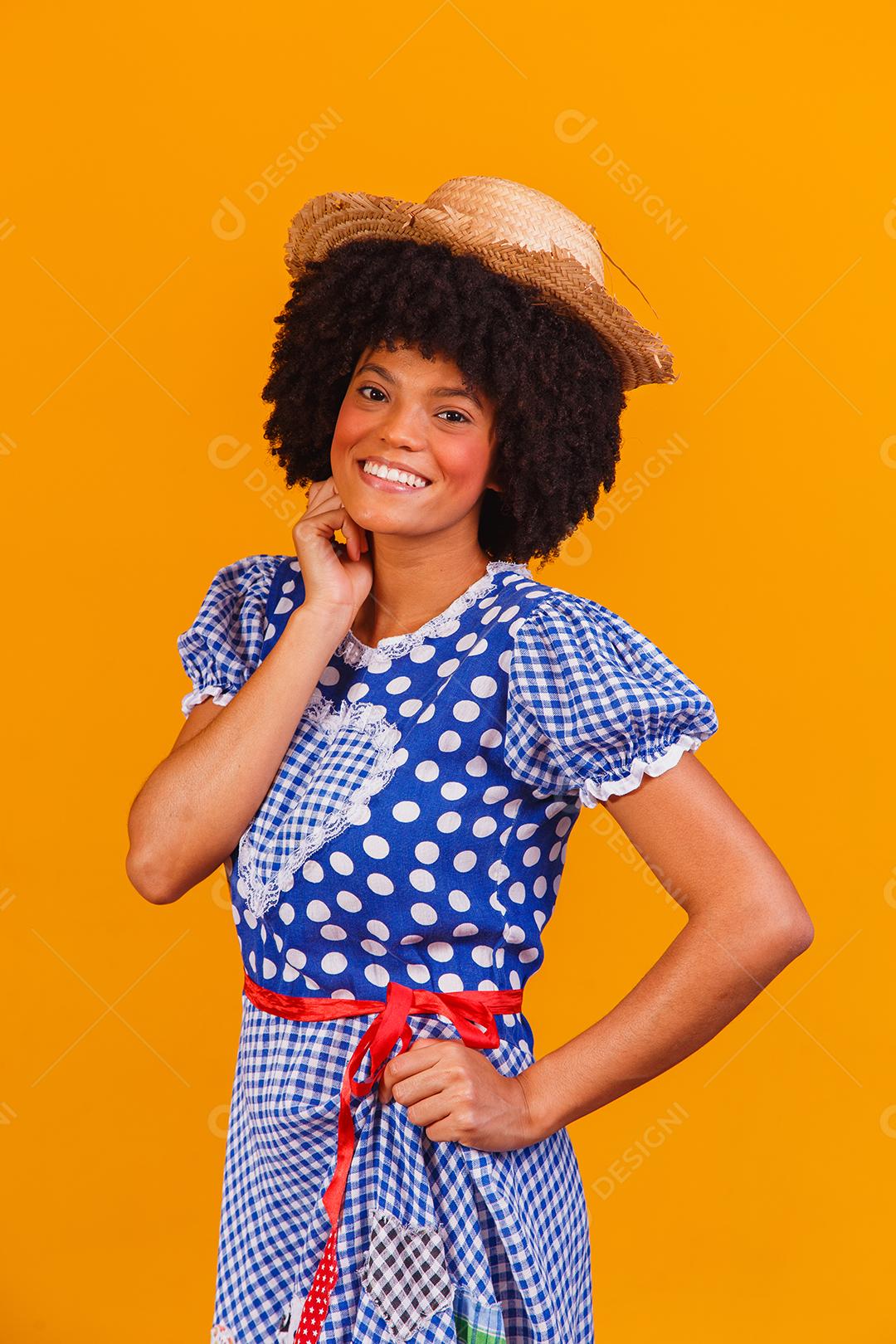 Mulher afro brasileira vestindo roupas típicas para a Festa Junina em fundo amarelo