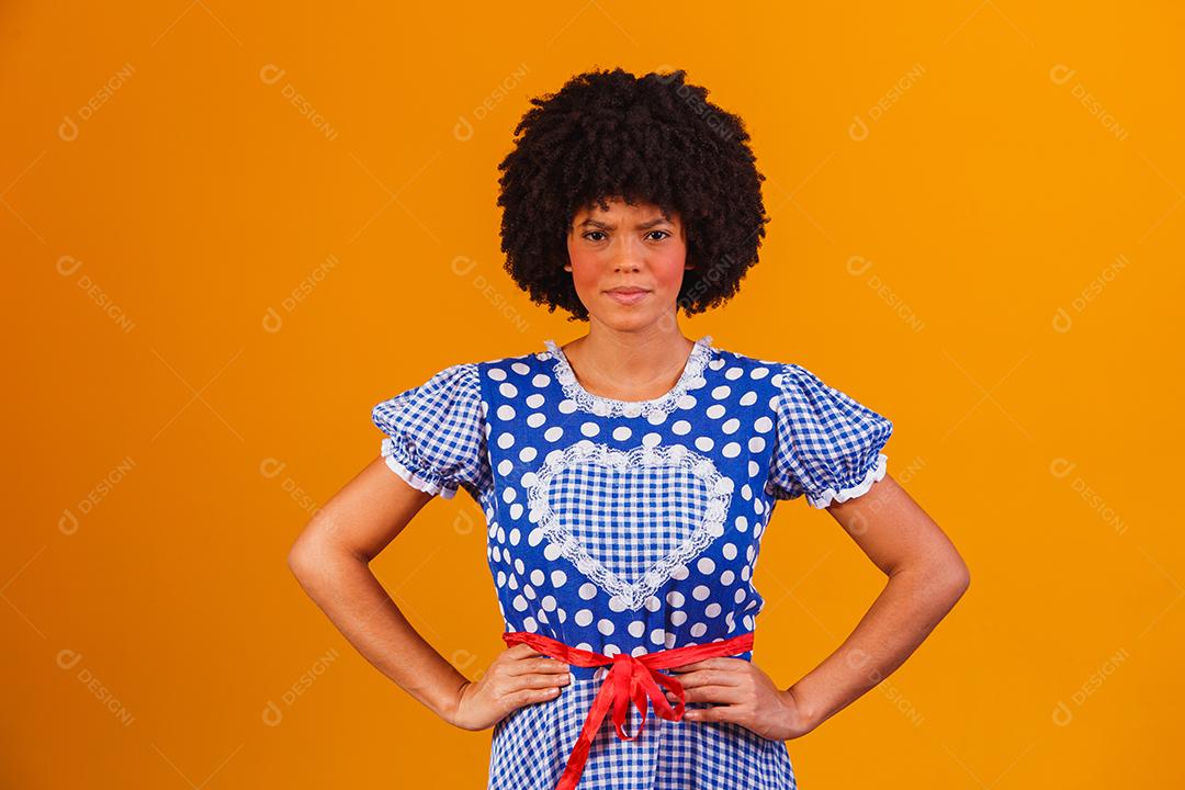 Mulher afro brasileira vestindo roupas típicas para a Festa Junina em fundo amarelo