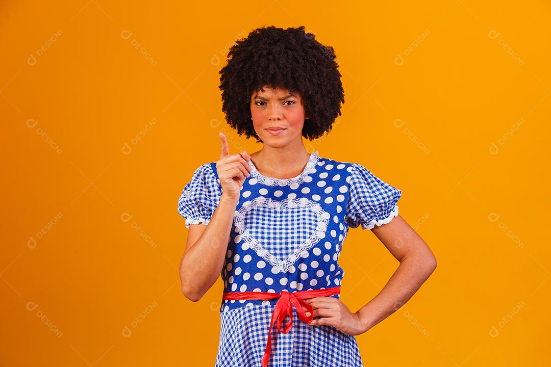 Mulher afro brasileira vestindo roupas típicas para a Festa Junina em fundo amarelo