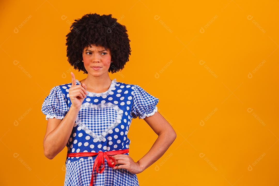 Mulher afro brasileira vestindo roupas típicas para a Festa Junina em fundo amarelo