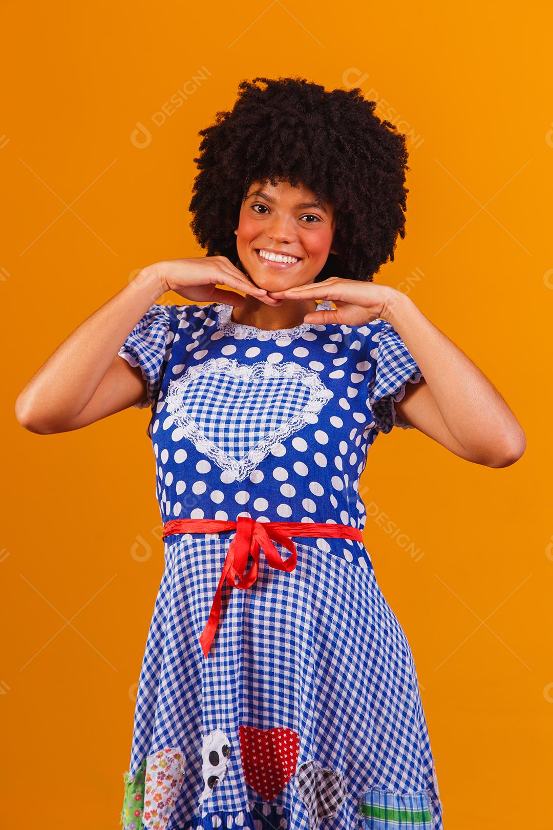 Mulher afro brasileira vestindo roupas típicas para a Festa Junina em fundo amarelo