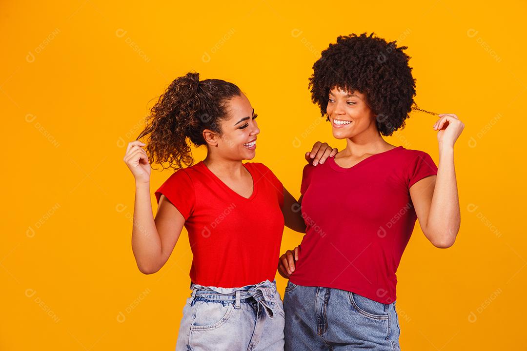Jovens amigas afro bonitas e felizes sorrindo para a câmera.
