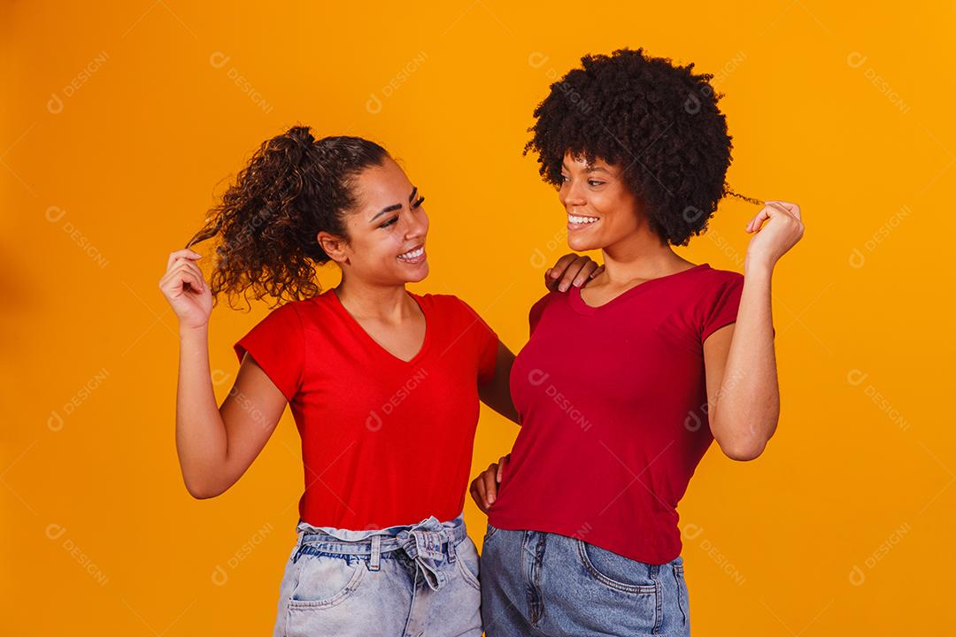 Jovens amigas afro bonitas e felizes sorrindo para a câmera.