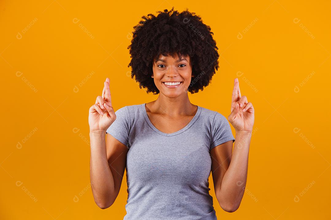 mulher afro com os dedos cruzados torcendo pela vitória