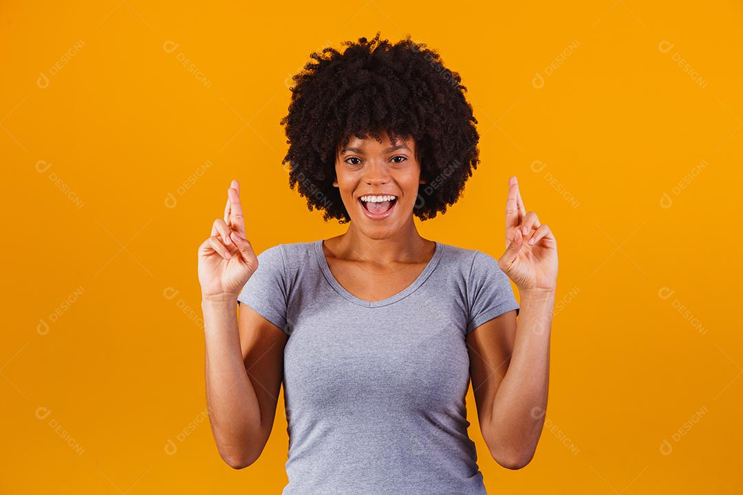 mulher afro com os dedos cruzados torcendo pela vitória