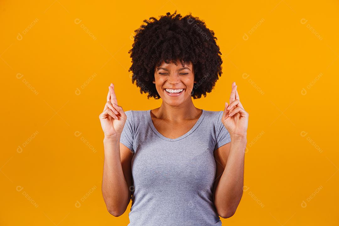 mulher afro com os dedos cruzados torcendo pela vitória