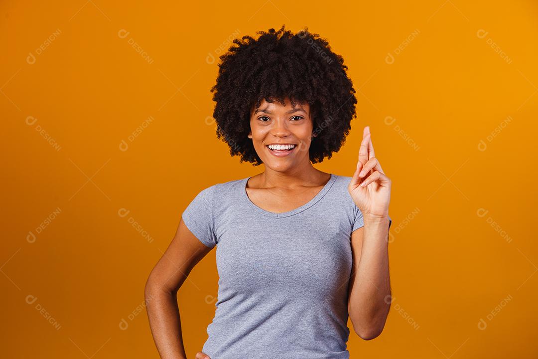 mulher afro com os dedos cruzados torcendo pela vitória