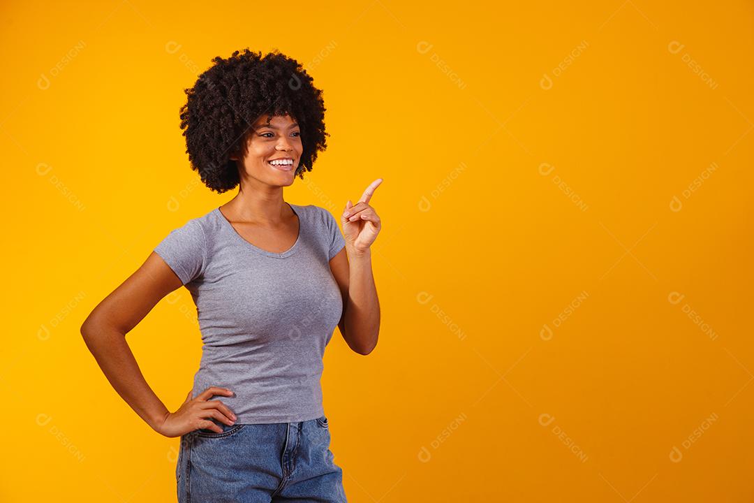 Mulher afro apontando em fundo amarelo