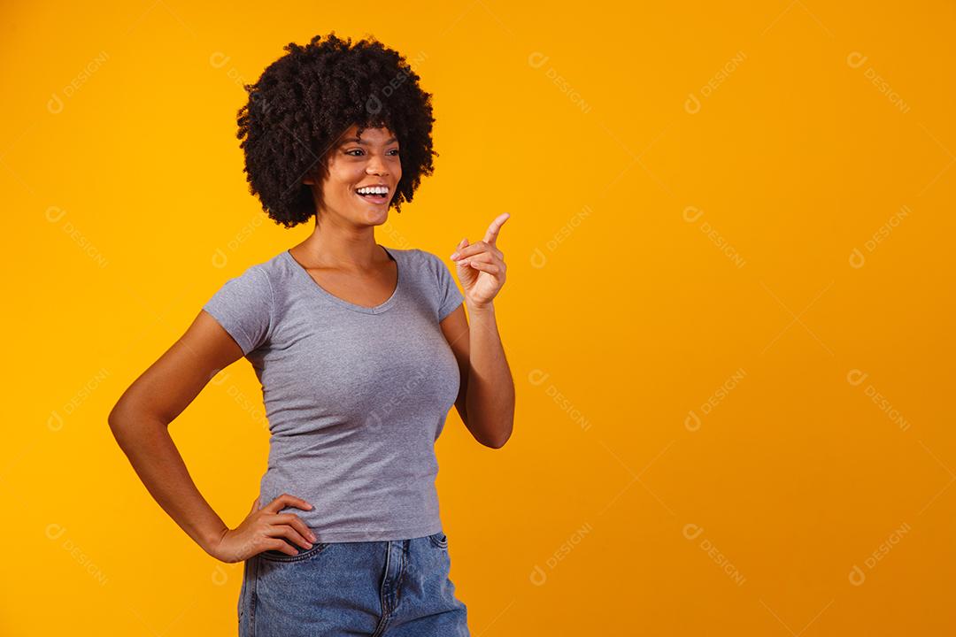 Mulher afro apontando em fundo amarelo