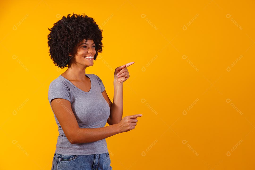 Mulher afro apontando em fundo amarelo