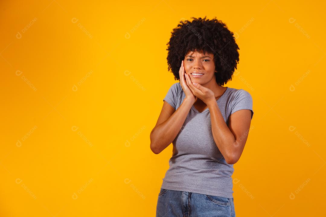 mulher afro com dor de dente em fundo amarelo