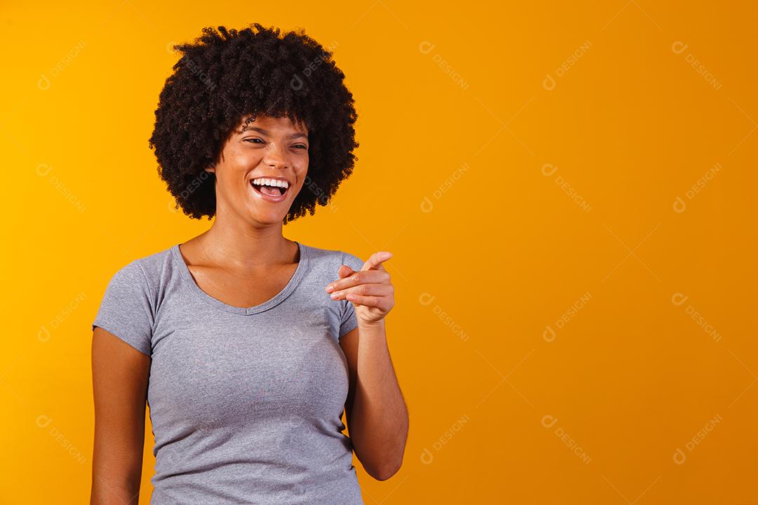 Mulher afro apontando em fundo amarelo