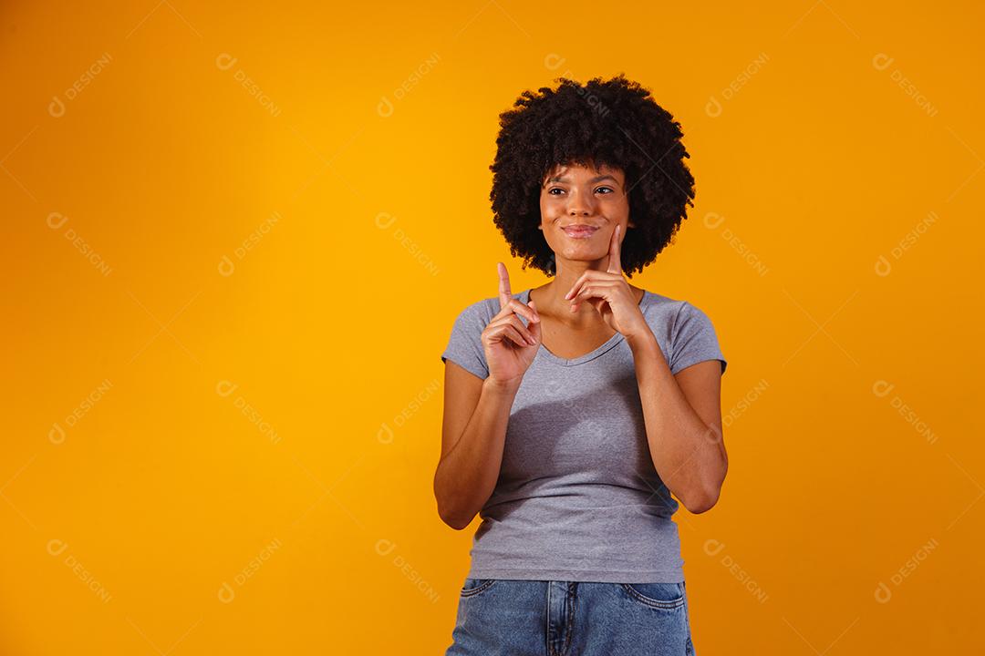 Mulher afro apontando em fundo amarelo