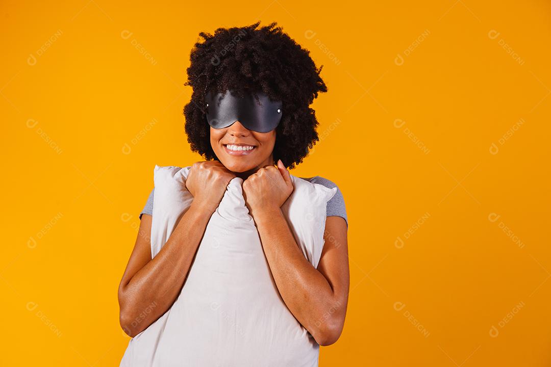 Dormindo. Sonhos. Retrato de mulher. Garota afro-americana de pijama e máscara de sono está abraçando um travesseiro