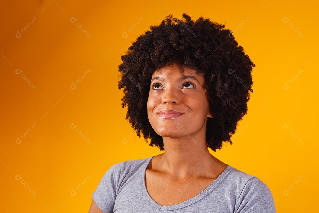 Mulher afro pensando em fundo amarelo