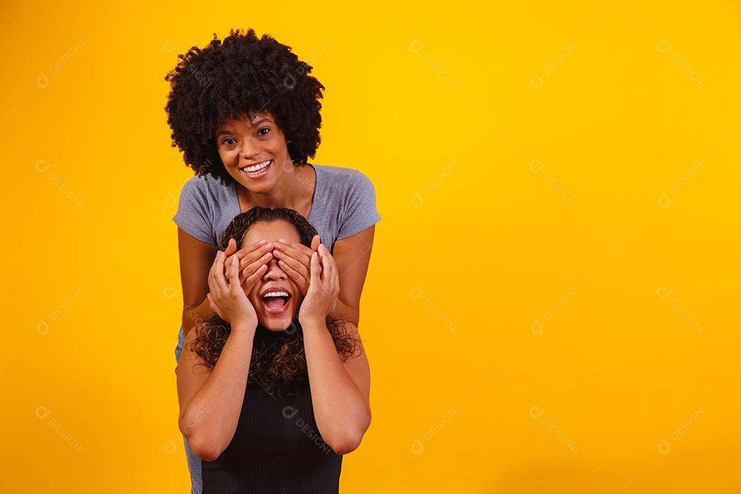 Filha tampado olhos de sua mãe sobre um fundo amarelo